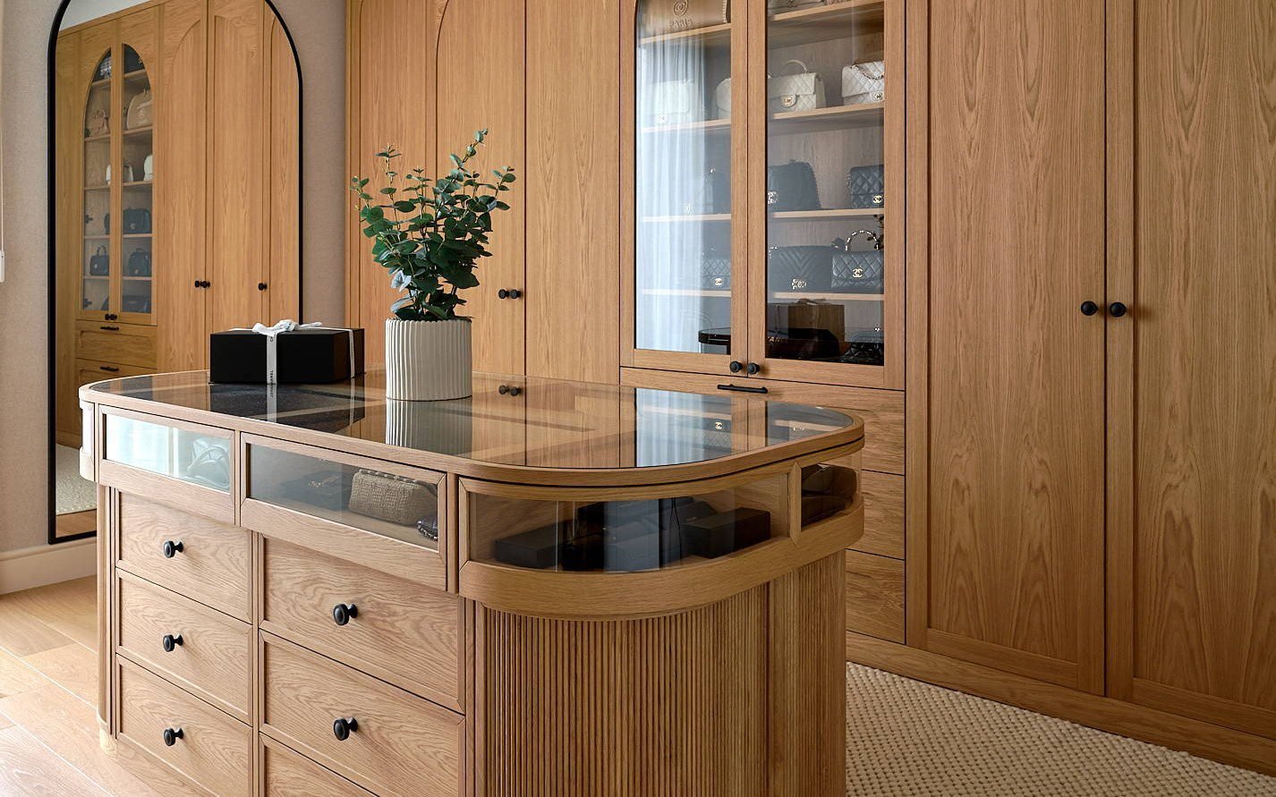 Warm wood wardrobe room with arched glass doors, round mirror and built-in units