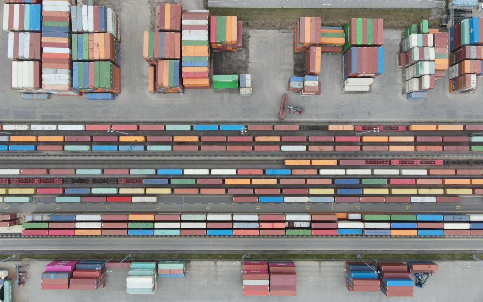 Aerial view of a container yard with rows of stacked cargo containers