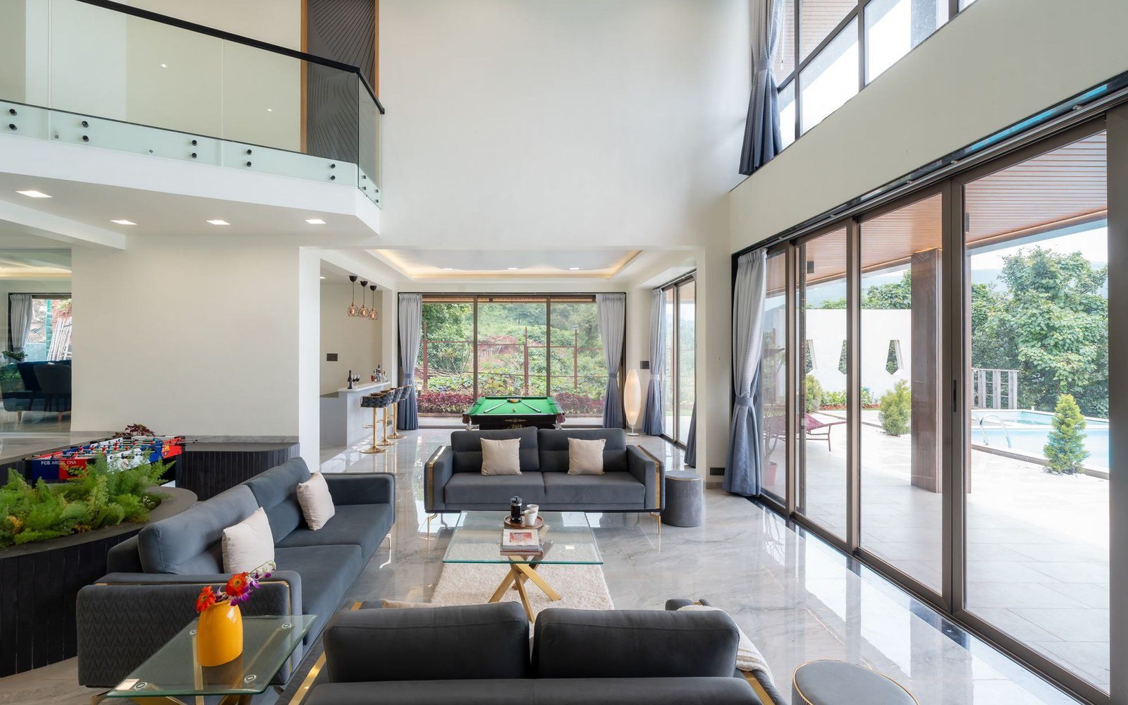 Double-height villa living room with a full-height sliding glass wall opening to the terrace