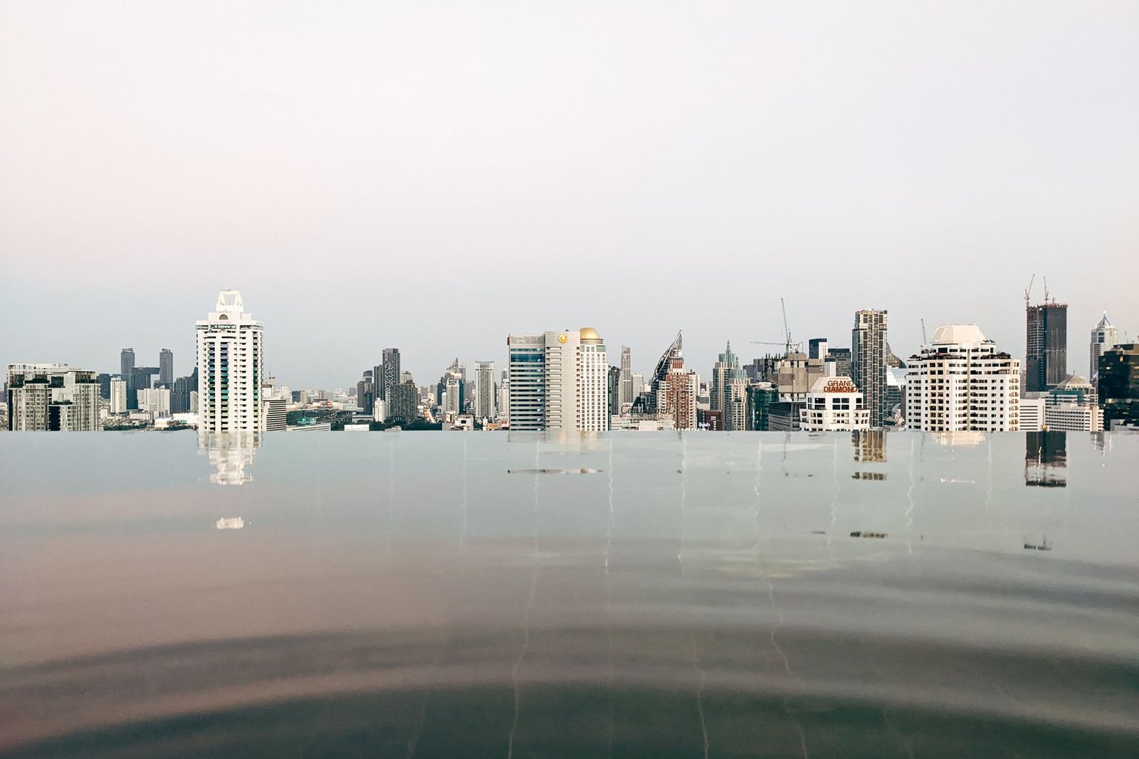 infinity pool edge meeting a dark anti-slip deck against a city skyline