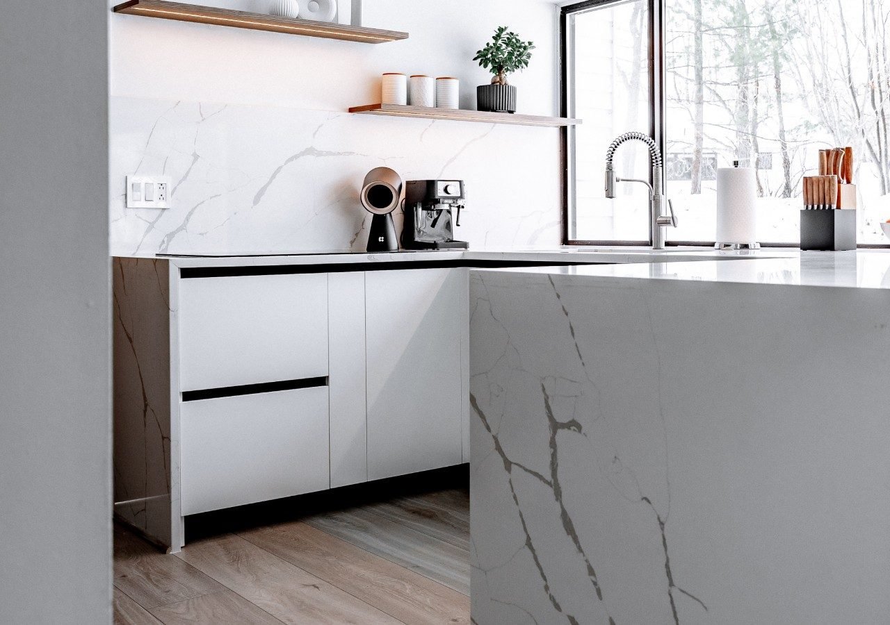 White gloss handleless kitchen with marble splashback and island