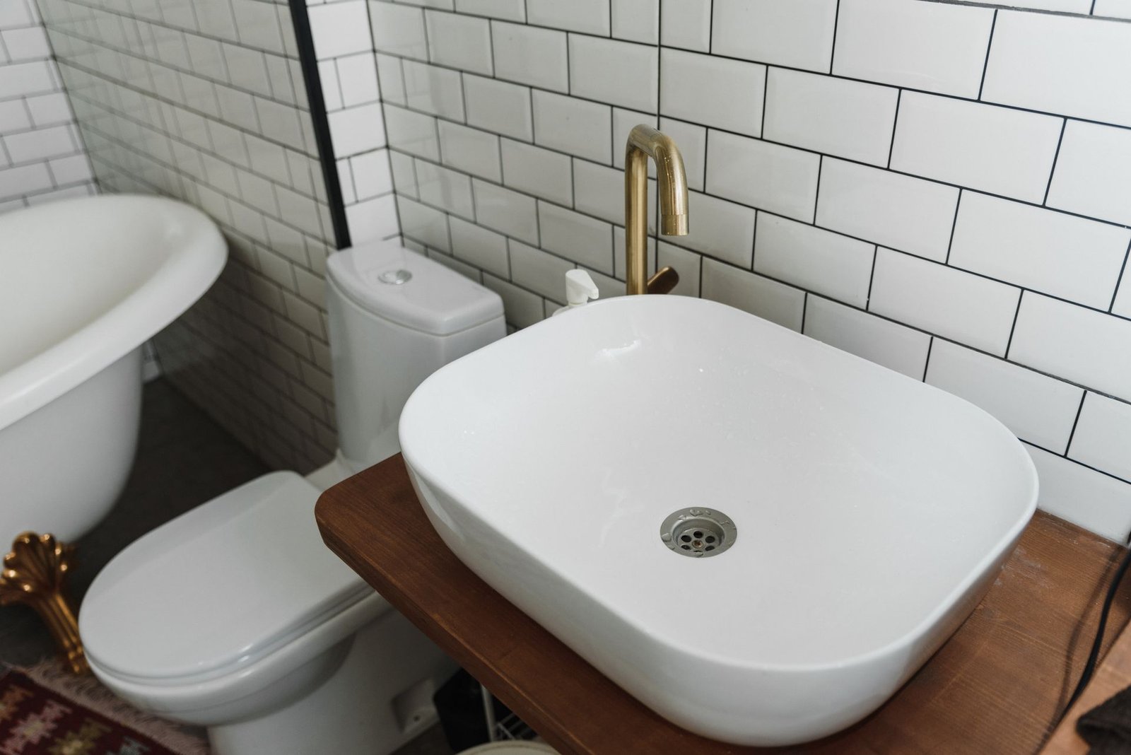 Gold tap with vessel basin in a white subway bathroom