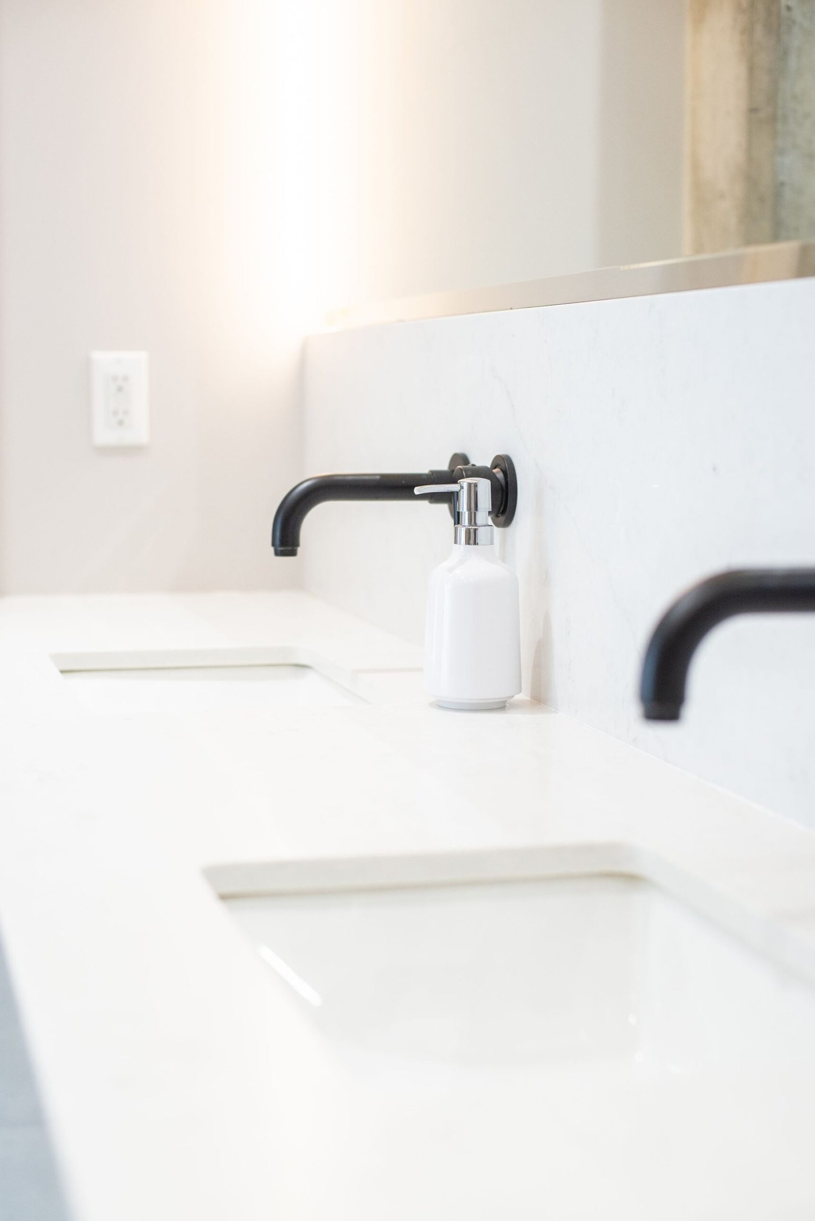 Matte black wall-mount tap in a white bathroom