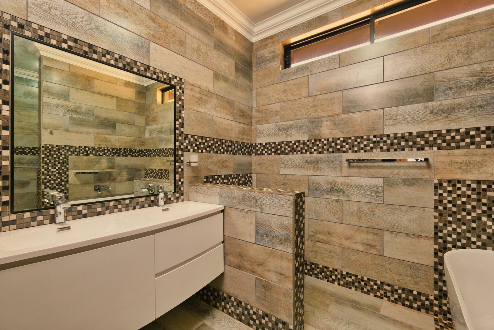 Travertine-look tile wall with cream vanity and mosaic inlay