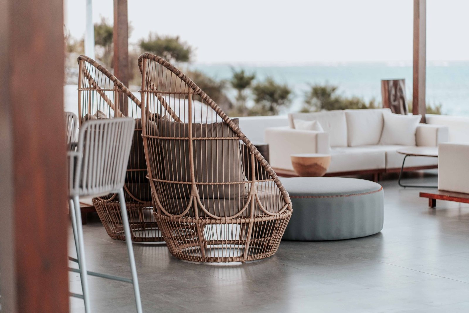 Wicker egg chairs and white sofa overlooking the sea