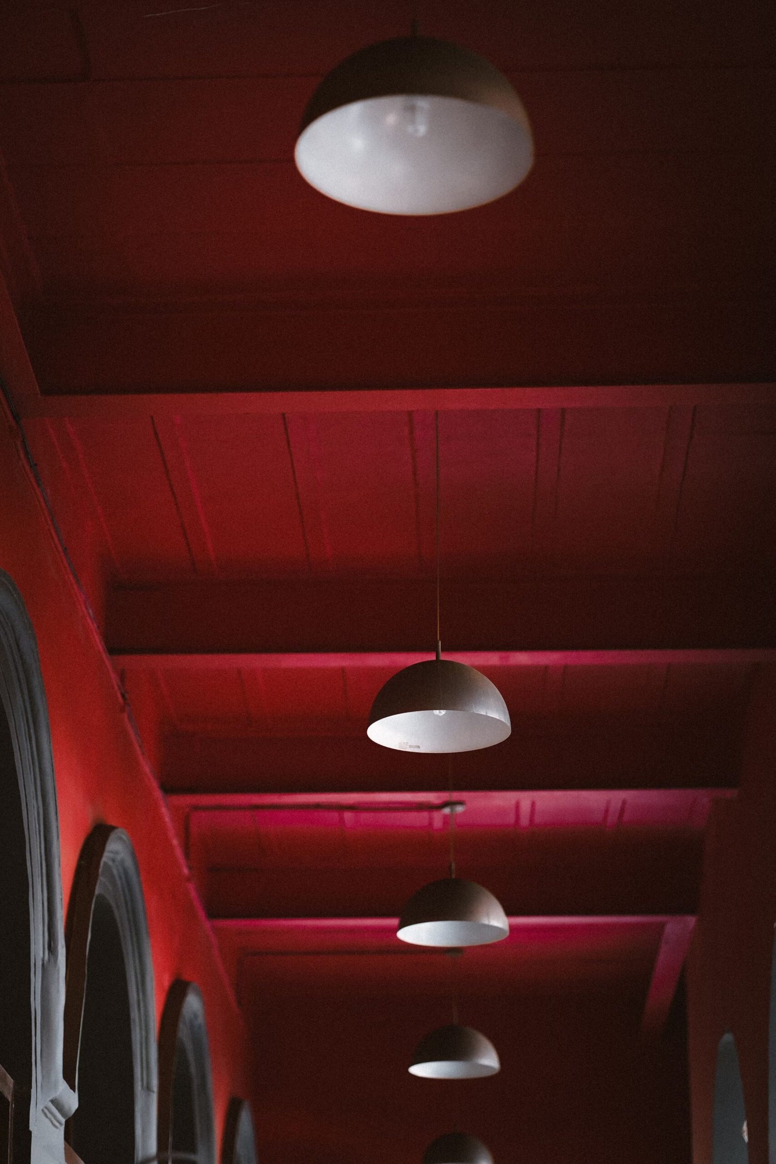 Row of dome ceiling lights along a red timber corridor