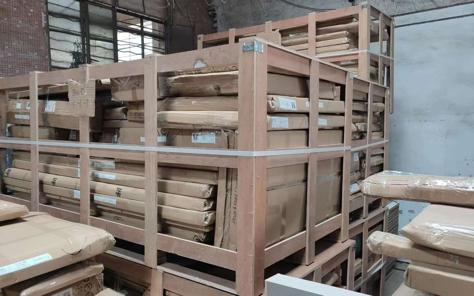 Timber-framed crates holding flat-packed cabinet panels in the packing hall before loading