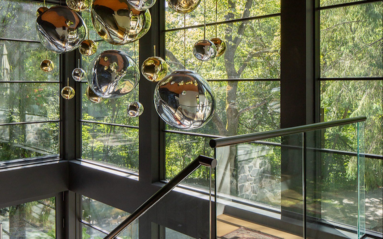 Cluster of glass pendant lights above a villa staircase with full height glazing
