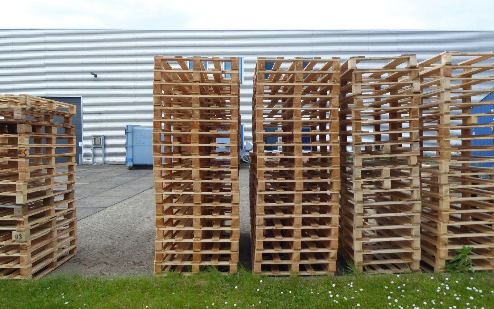 Stacks of wooden pallets outside an industrial warehouse