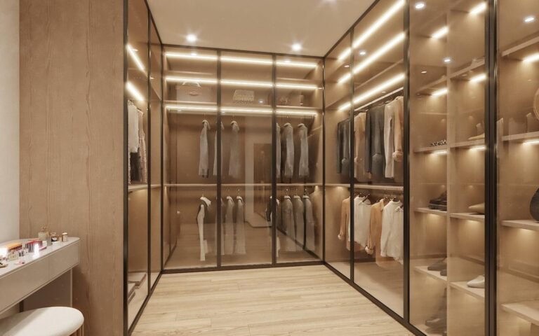 Warm lit walk-in closet with glass front shelving and hanging rails in a villa master bedroom